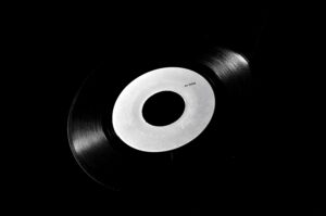 Classic black vinyl record with a white label on a dark background, symbolizing retro music nostalgia.